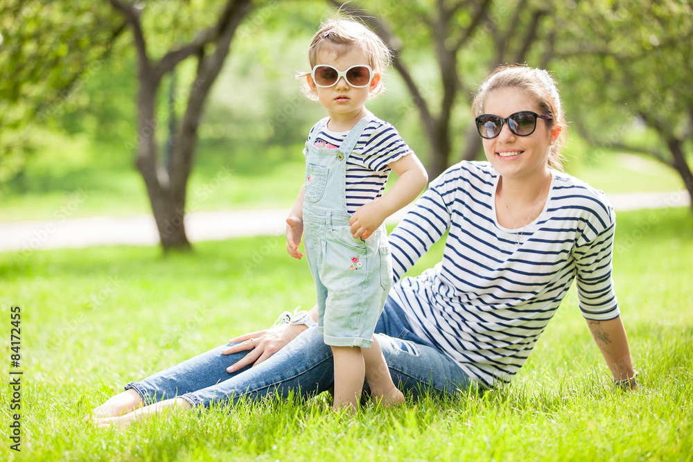Fototapeta premium Portrait of a beautiful young woman with a small child in park