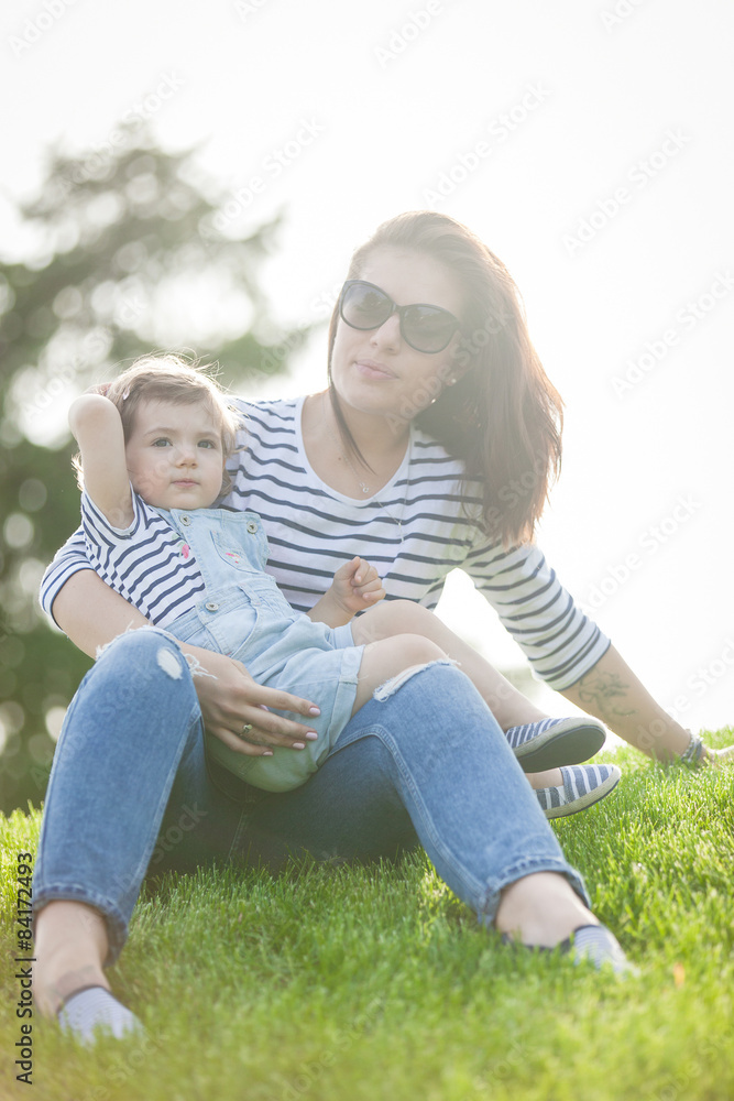 Fototapeta premium Portrait of a beautiful young woman with a small child in park