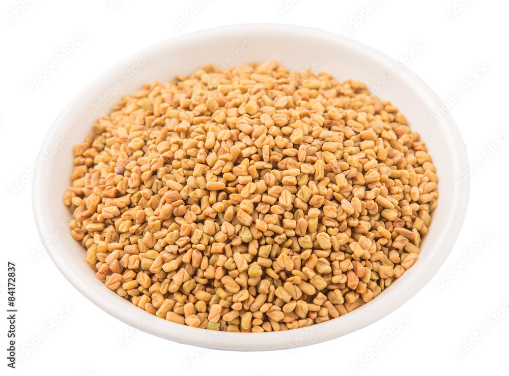 Fenugreek seeds in white bowl over white background Fenugreek seeds in white bowl over white background