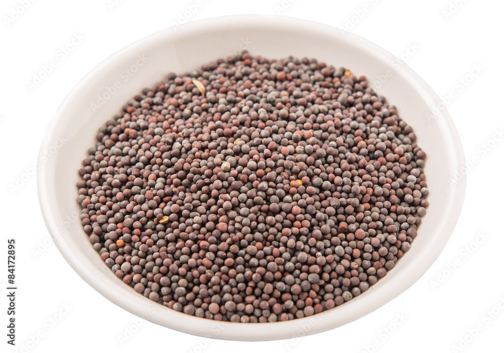 Black mustard seed in white bowl over white background Black mustard seed in white bowl over white background
