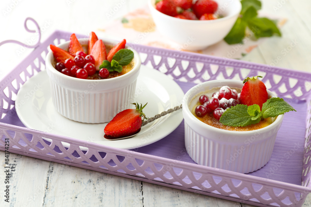 Creme brulee dessert with fresh strawberries and mint leaves, on color wooden background Creme brulee dessert with fresh strawberries and mint leaves, on color wooden background