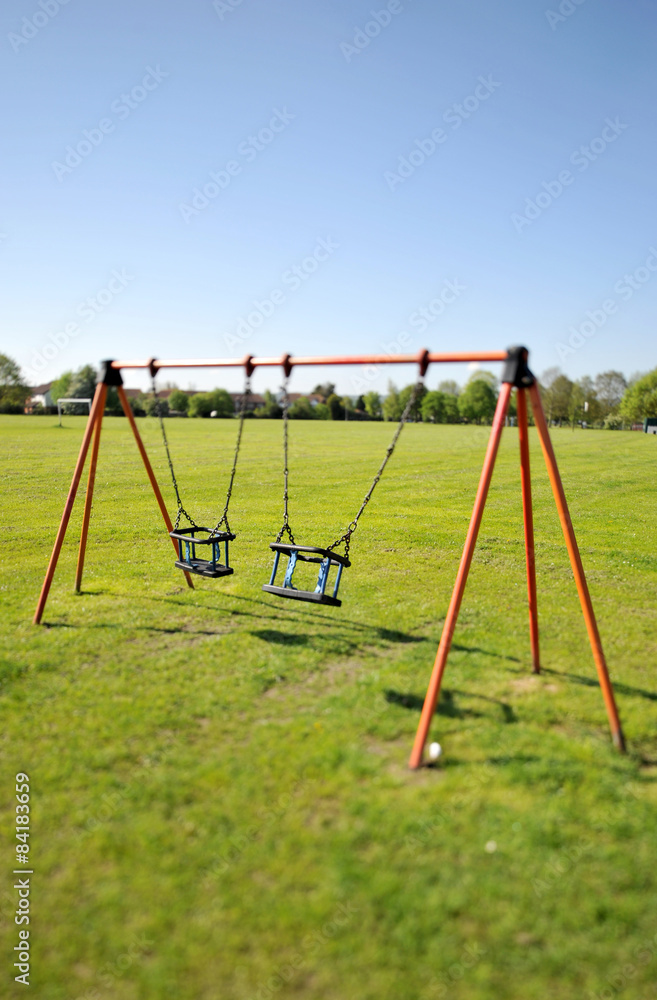 Eerie view of swings swinging on there own in a park Eerie view of swings swinging on there own in a park