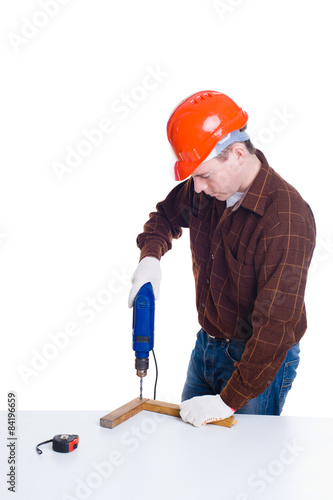 Portrait of man in helmet drilling a plank of wood