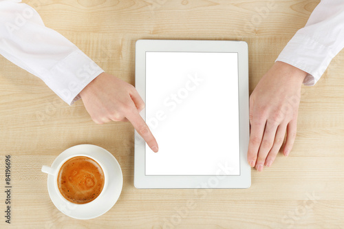Hands with tablet and cup of coffee, on wooden table
