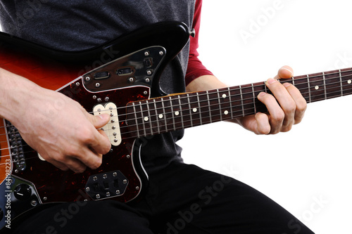 Young man playing on electric guitar close up