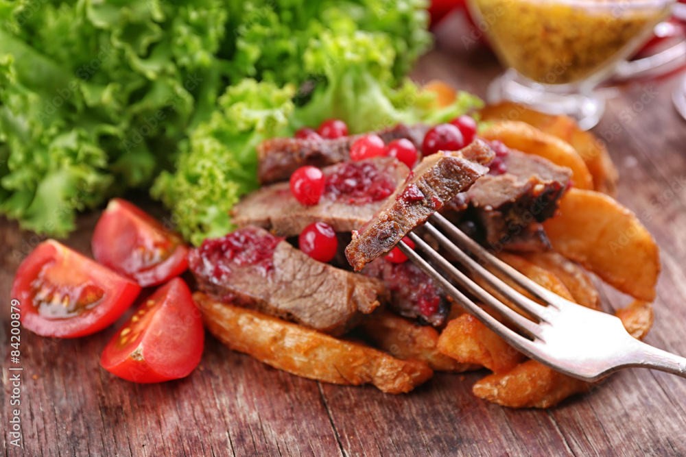 Beef with cranberry sauce, roasted potato slices and bun on cutting board, on wooden background Beef with cranberry sauce, roasted potato slices and bun on cutting board, on wooden background