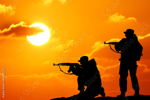 Silhouette shot of soldier holding gun with colorful sky and mou © YURII Seleznov