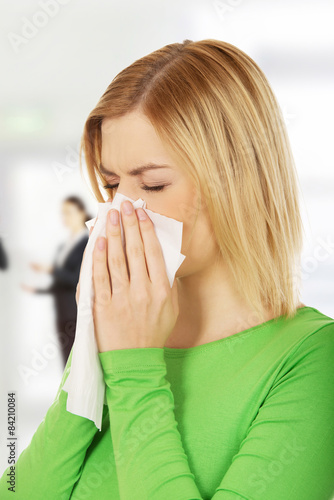 Woman sneezing to tissue.