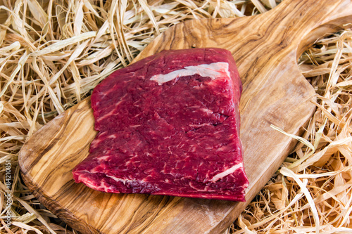 British Beef Flat Iron steak on cutting board and straw photo