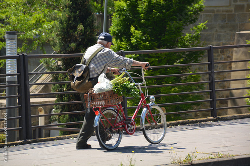 hombre mayor empujando una bicicleta © uzkiland