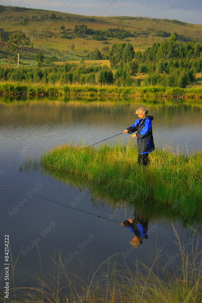Lady fly fishing, calm water, late afternoon Lady fly fishing, calm water, late afternoon