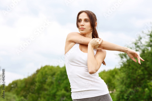 Young sportive girl stretching her arms