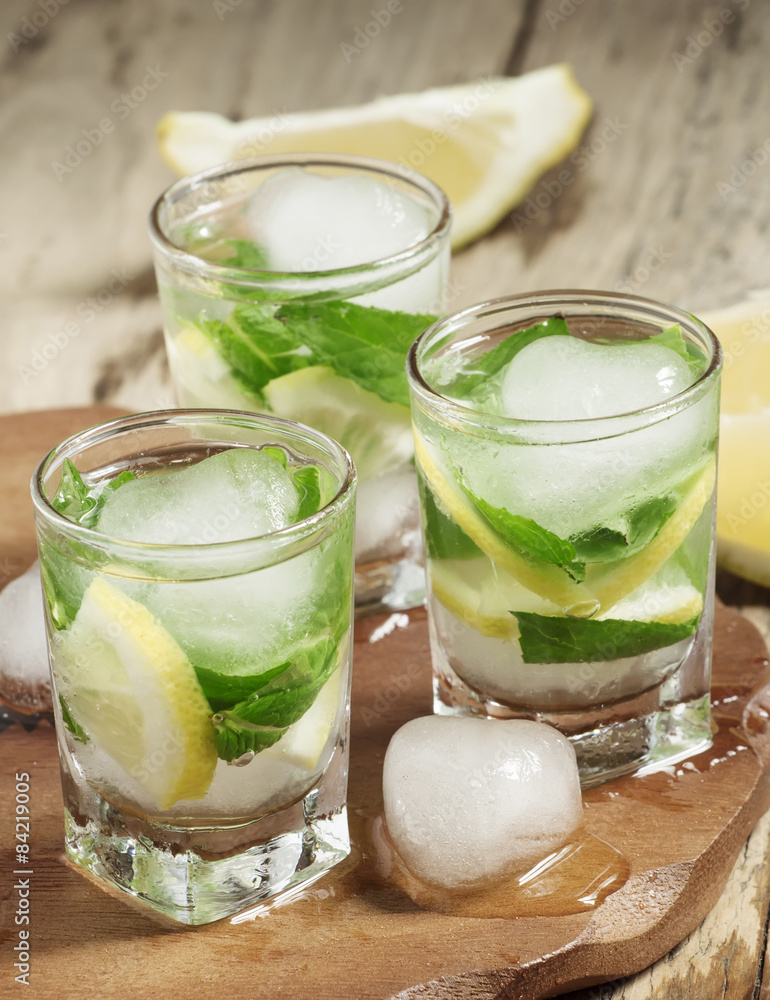 Glass of water with fresh lemon, ice and mint, selective focus Glass of water with fresh lemon, ice and mint, selective focus