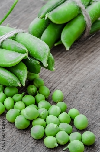 Green organic peas on wooden background, shallow focus