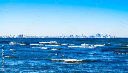 Waves breaking on lake with Toronto skyline on distant horizon.