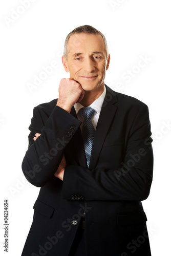 Happy mature businessman with hand under chin