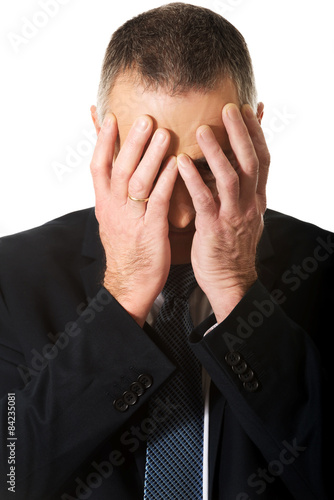 Portrait of stressed businessman covering his face