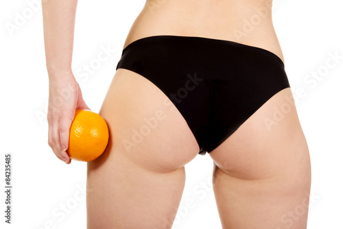 Female buttocks and orange in hand.