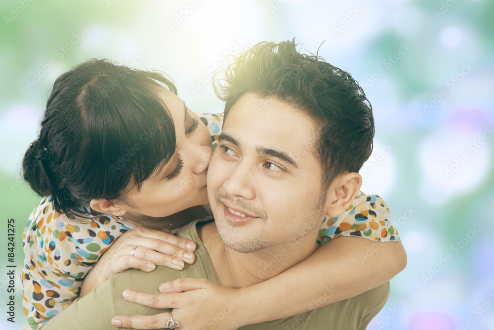 Fototapeta premium Woman kiss her boyfriend with bokeh background