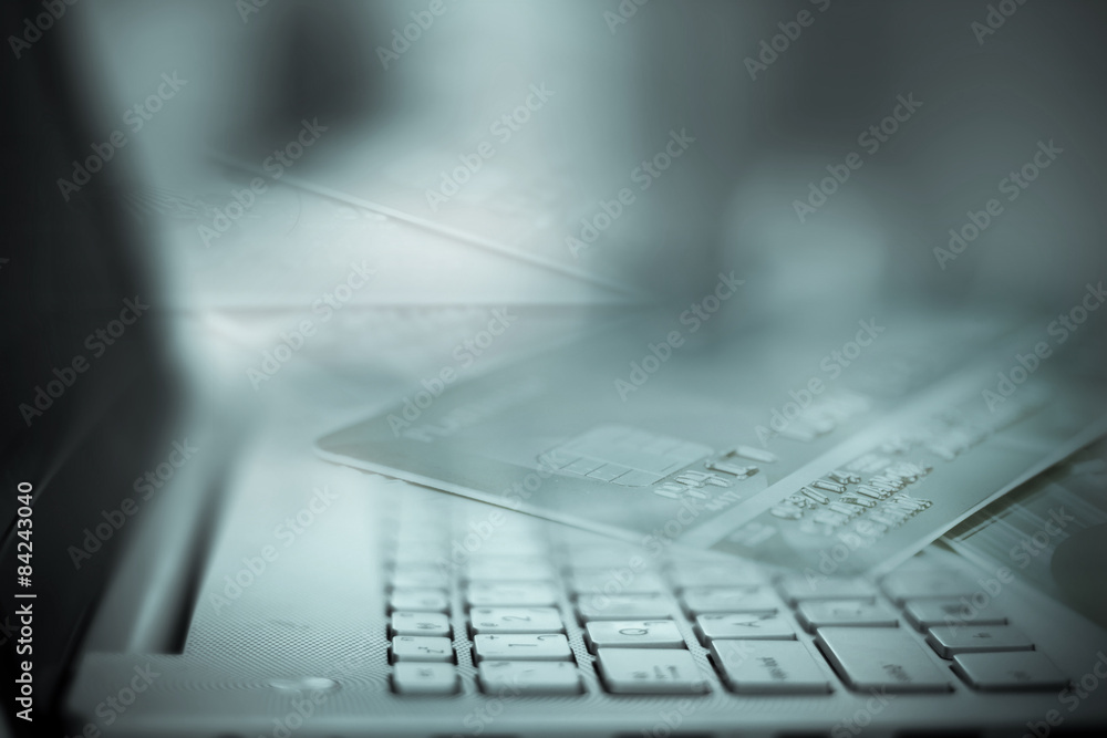 fade off credit card and silver laptop computer fade off credit card and silver laptop computer
