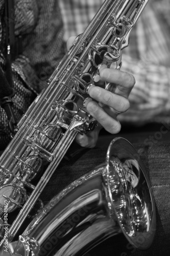 The saxophone in the hands of a musician in grayscale