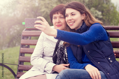 mother and adult daughter are doing Selfe outdoors