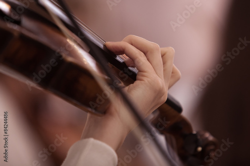 The hand of the girl playing the violin in dark colors