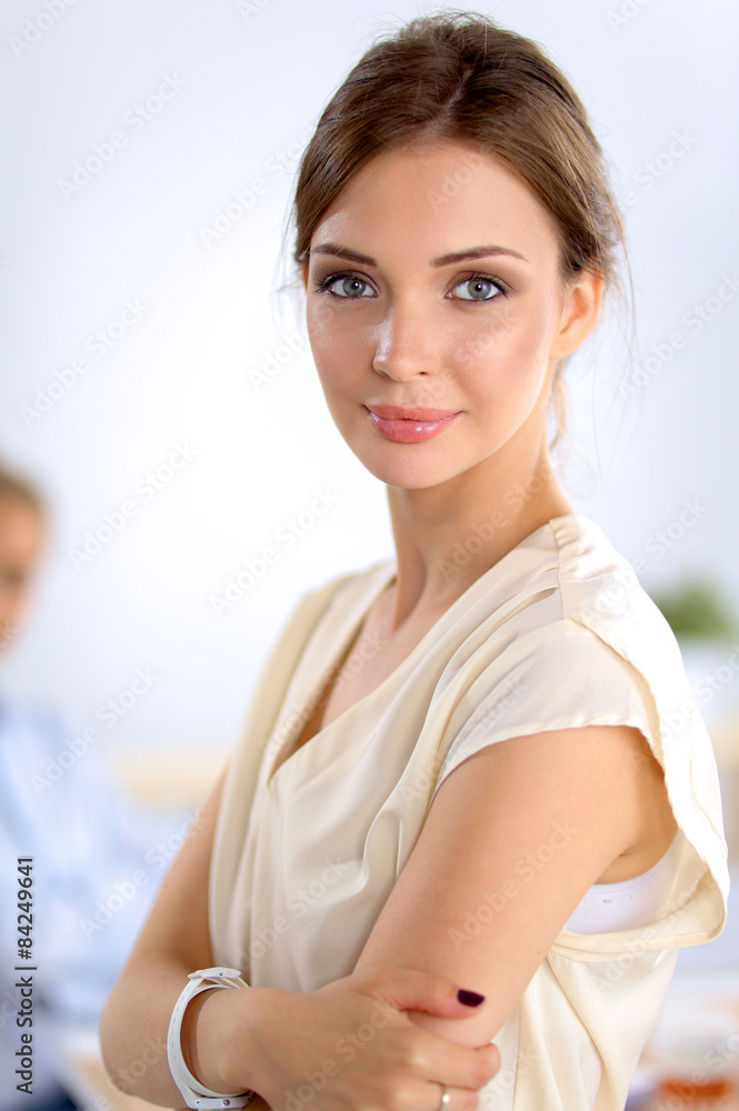 Attractive businesswoman standing near wall in office