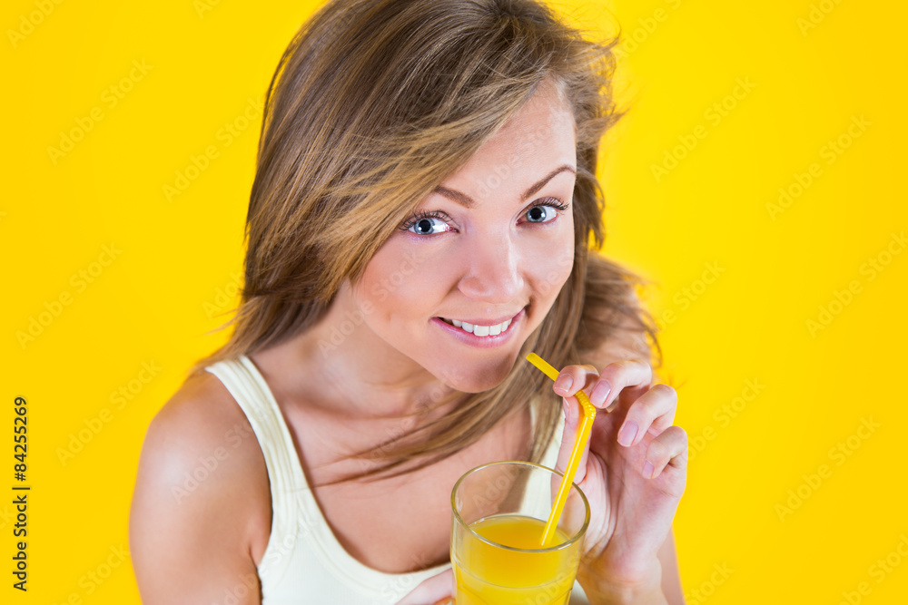 Teenager girl drinking orange juice on yellow background Teenager girl drinking orange juice on yellow background