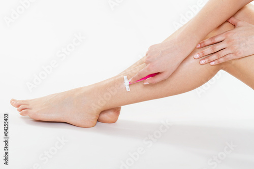 Woman is shaving her leg on white background
