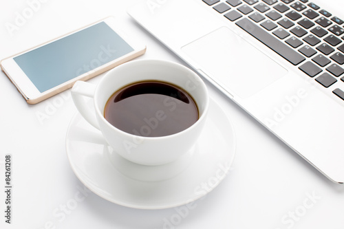 Modern laptop with mobile phone and cup of coffee