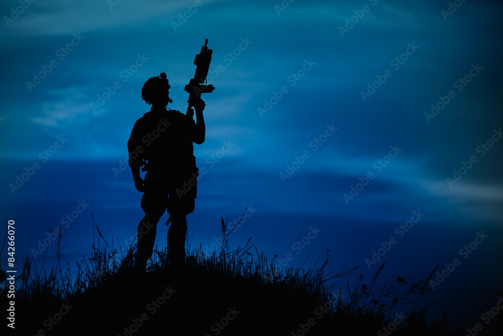 Fototapeta premium Silhouette of military soldier or officer with weapons at night.