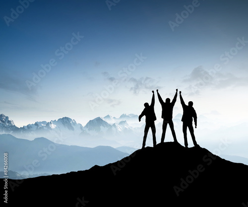 Silhouettes of team on mountain peak
