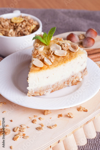 piece of cheesecake with nut on wooden board, vertical