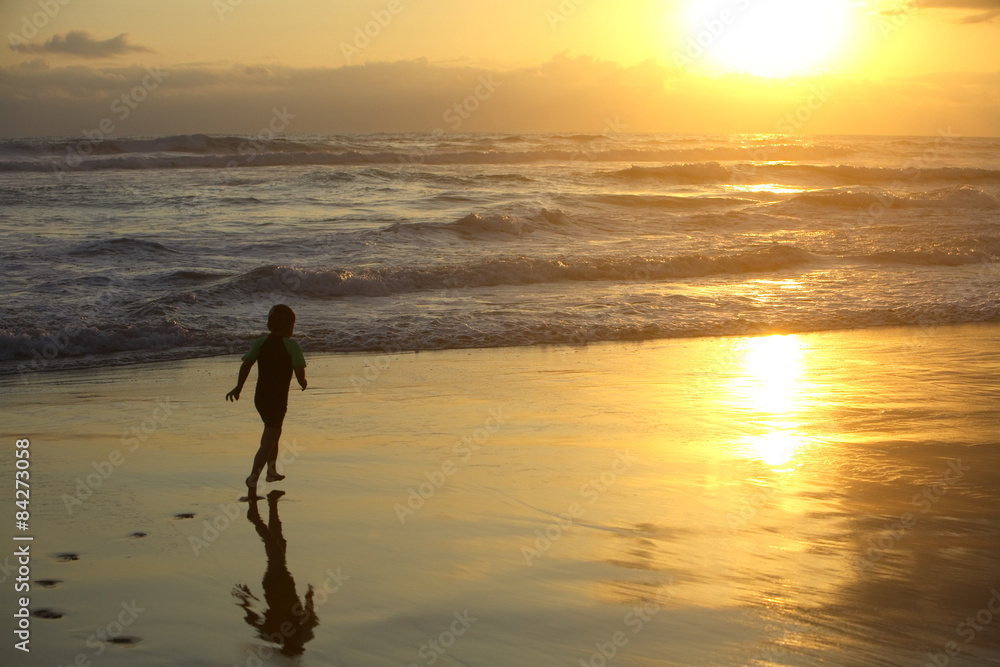 Boy running on the beach at sunset
