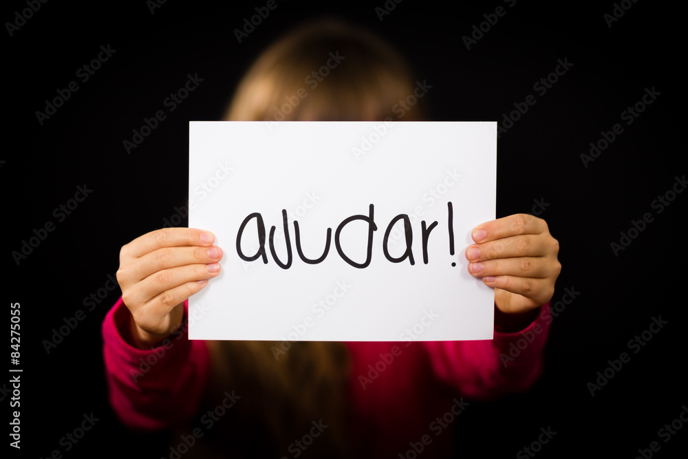 Child holding sign with Portuguese word Ajudar - Help Child holding sign with Portuguese word Ajudar - Help