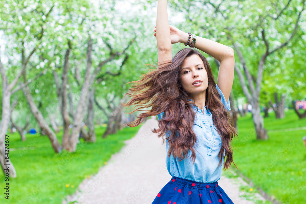Naklejka premium Attractive woman with flying hair spinning in park
