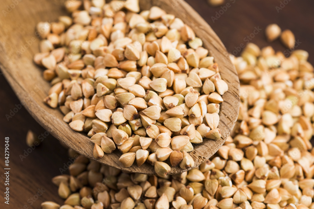 Fototapeta premium Buckwheat with a spoon on a wooden boards background