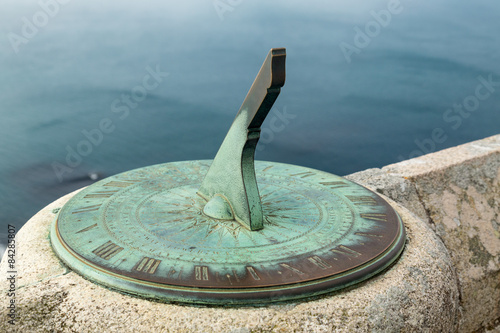 Brass or copper sun dial fixed to stone wall of castle