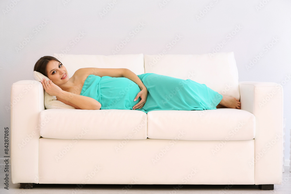 Pregnant woman lying on sofa in room Pregnant woman lying on sofa in room