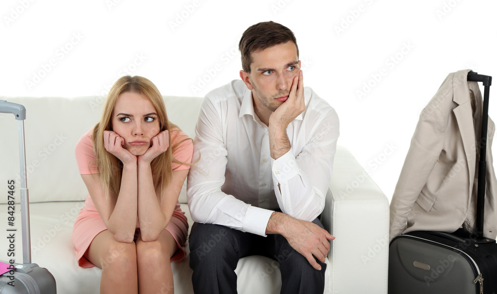 Portrait of young happy couple with baggage, sitting on sofa. Isolated on white Portrait of young happy couple with baggage, sitting on sofa. Isolated on white