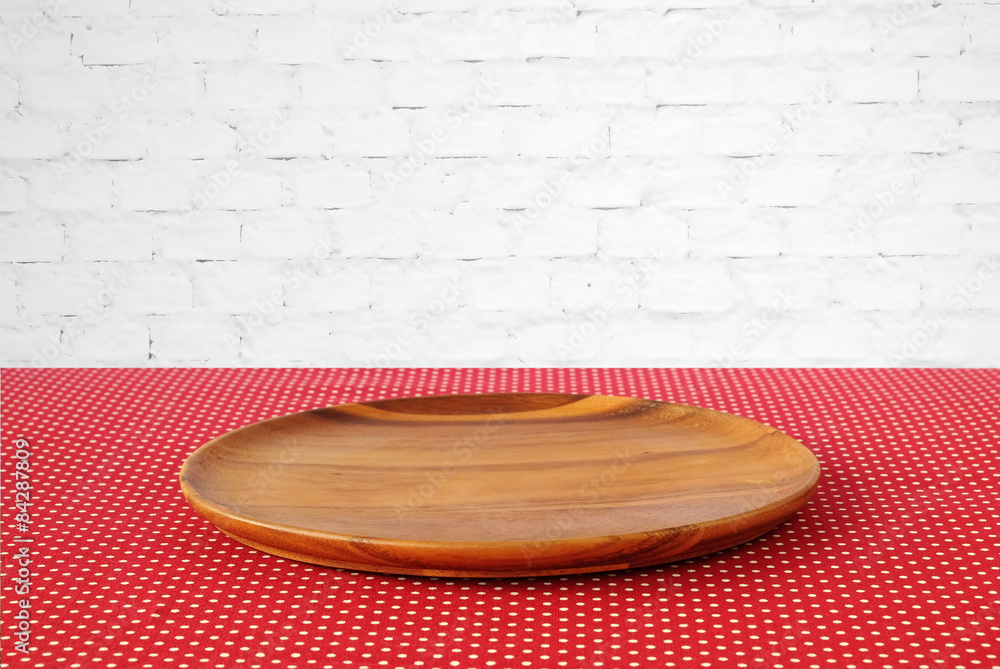 Empty round wooden tray on red polka dot tablecloth. Empty round wooden tray on red polka dot tablecloth.