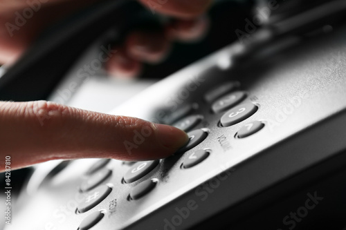 Foto Finger pressing number button on telephone to make a call, close up