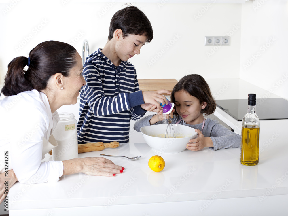 Niños cocinando mientras su madre les observa Niños cocinando mientras su madre les observa