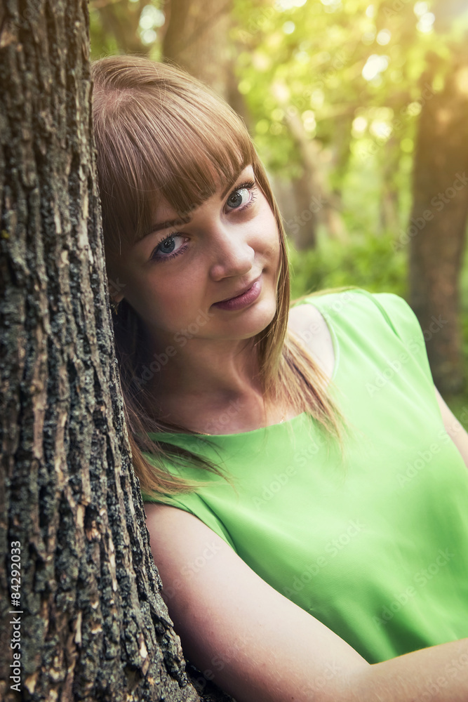 Naklejka premium Young sensual girl leaning against a tree