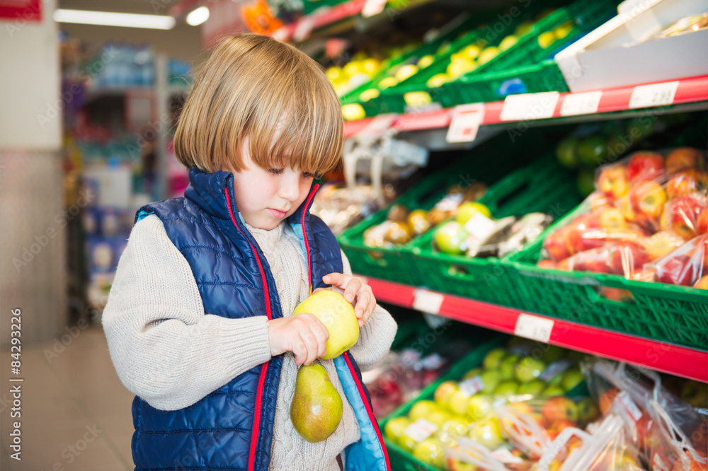 Little boy choosing fruits in a food store