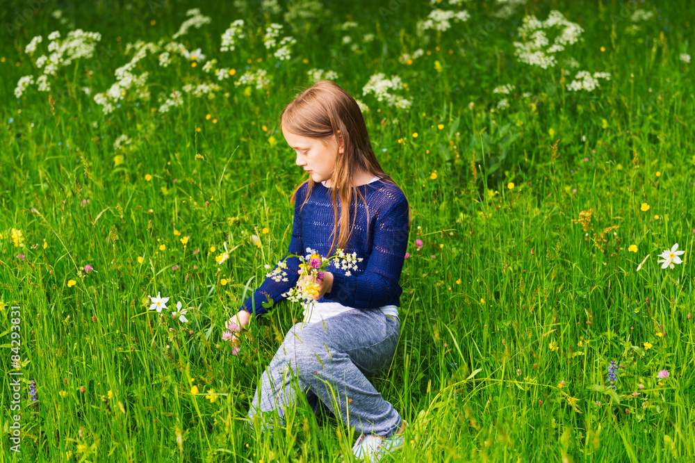 Fototapeta premium Cute little girl picking wildflowers