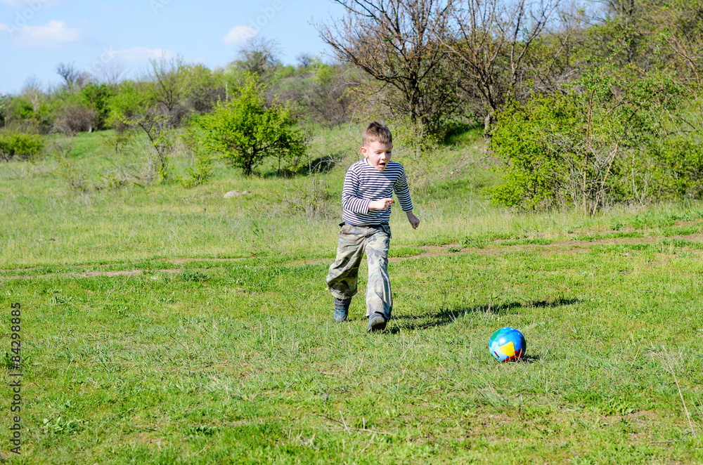 Fototapeta premium Boy Kicking Colorful Soccer Ball in Field