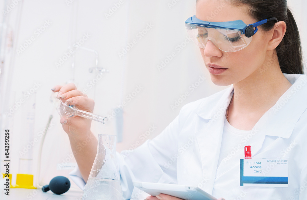 young woman scientist in glasses working and observing liquid at young woman scientist in glasses working and observing liquid at