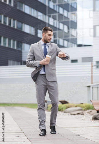young serious businessman with paper cup outdoors © Syda Productions